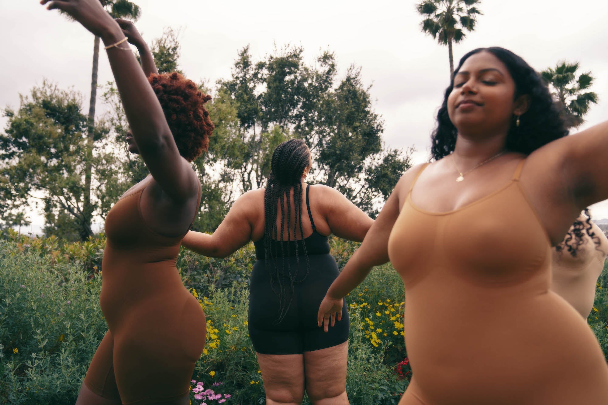 three models dancing in proclaim's plant-based shapewear collection in inclusive nude tones and black