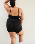 Sustainable shapewear back side of model in black plant-based shapewear mid-thigh bodysuit made from evo and creora