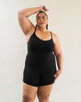 Sustainable shapewear front view of model in black plant-based shapewear mid-thigh bodysuit made from evo and creora