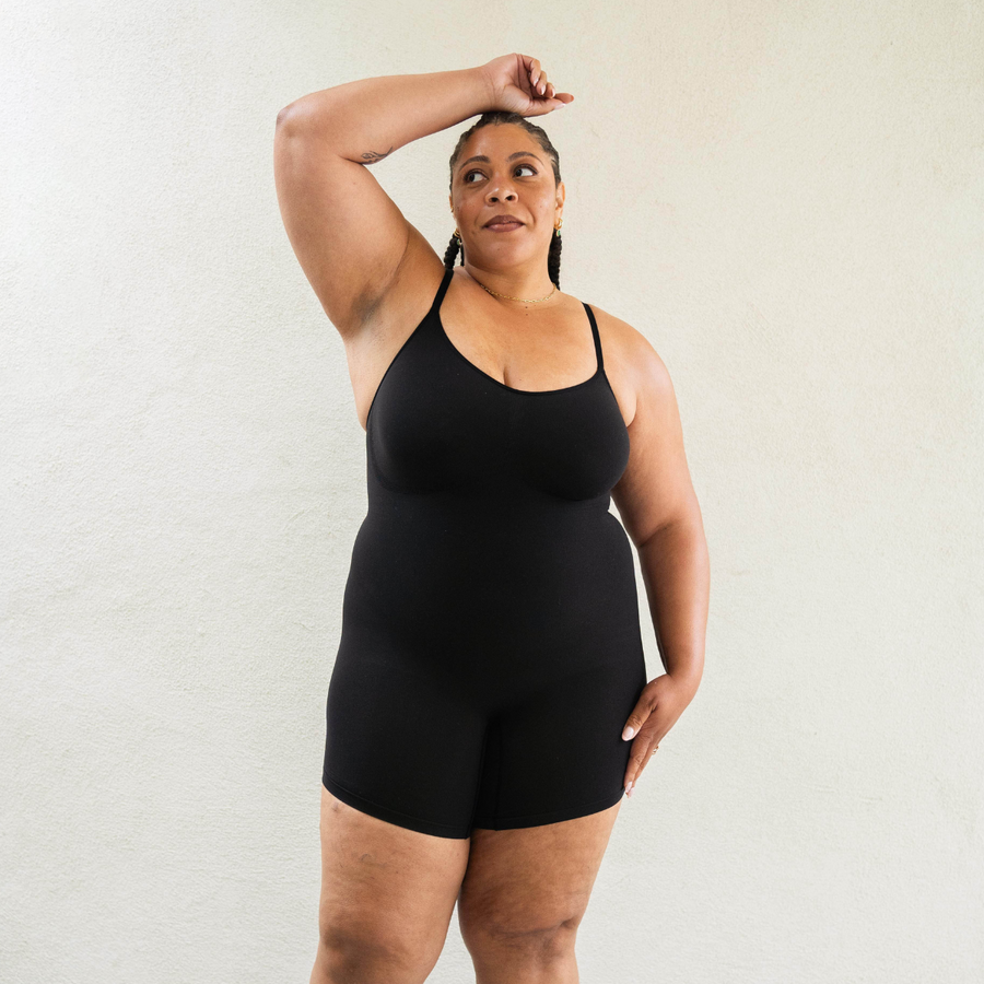 Sustainable shapewear front view of model in black plant-based shapewear mid-thigh bodysuit made from evo and creora
