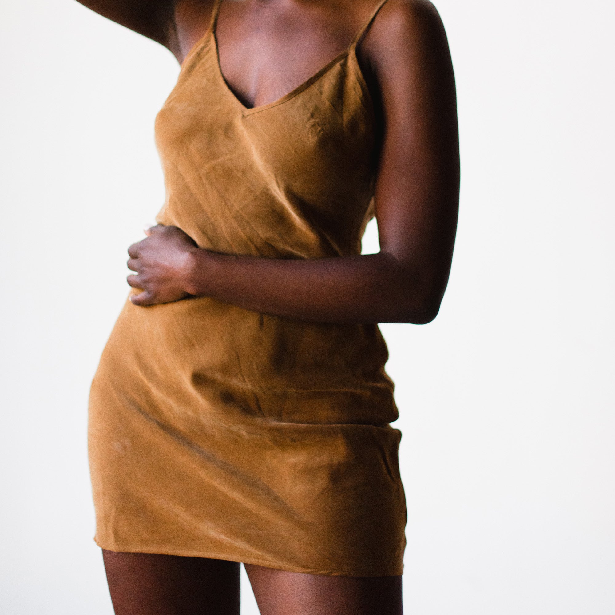 model wears a vegan slip dress sustainably made of cupro in a brown deep nude tone we call ella nude..